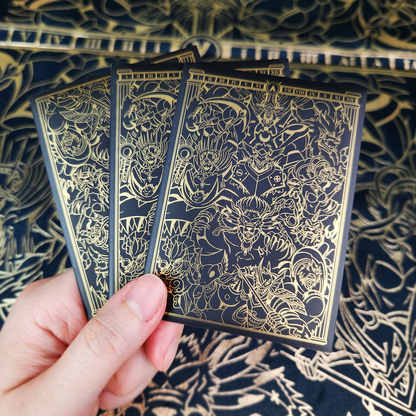 Three illustrated playing cards with dark backs featuring intricate gold line art, set against a matching patterned navy and gold surface.