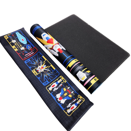 A black gaming playmat with mecha robot graphics, shown partially unrolled alongside a matching rolled-up playmat bag on a white background.